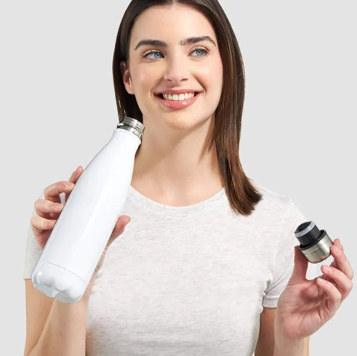 Woman holding a white water bottle with a silver cap against a light gray background